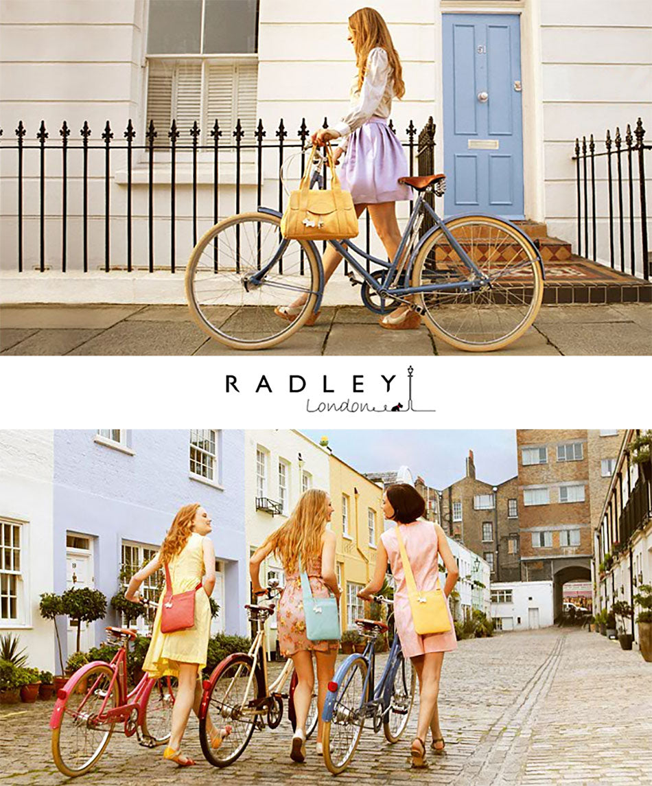 Women carrying colourful Radley Bags whilst pushing Pashley Britannia and Poppy bicycles in a mews in London.