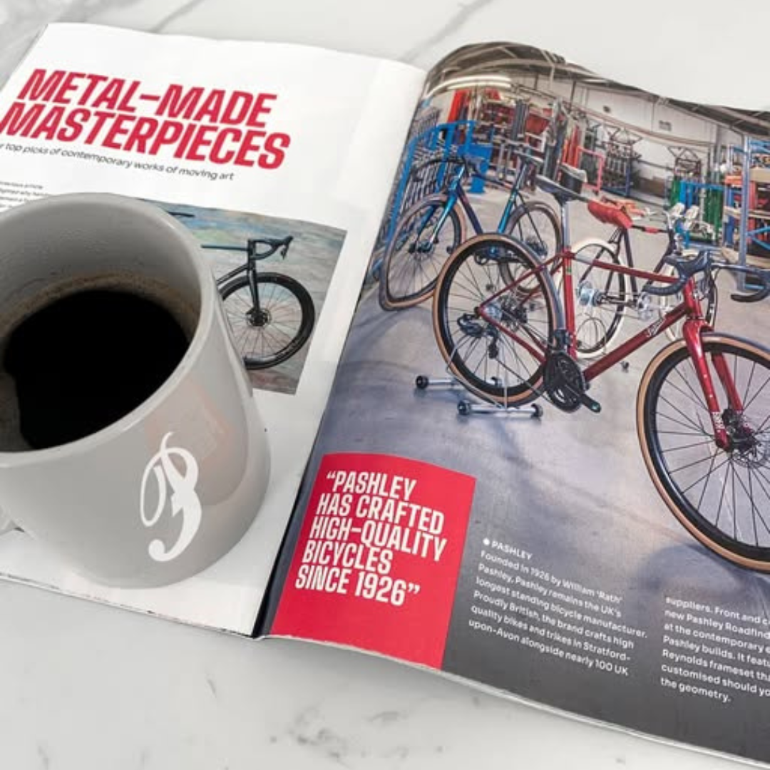 Open magazine showing photos of Pashley bikes within the bike factory, with a grey coffee cup