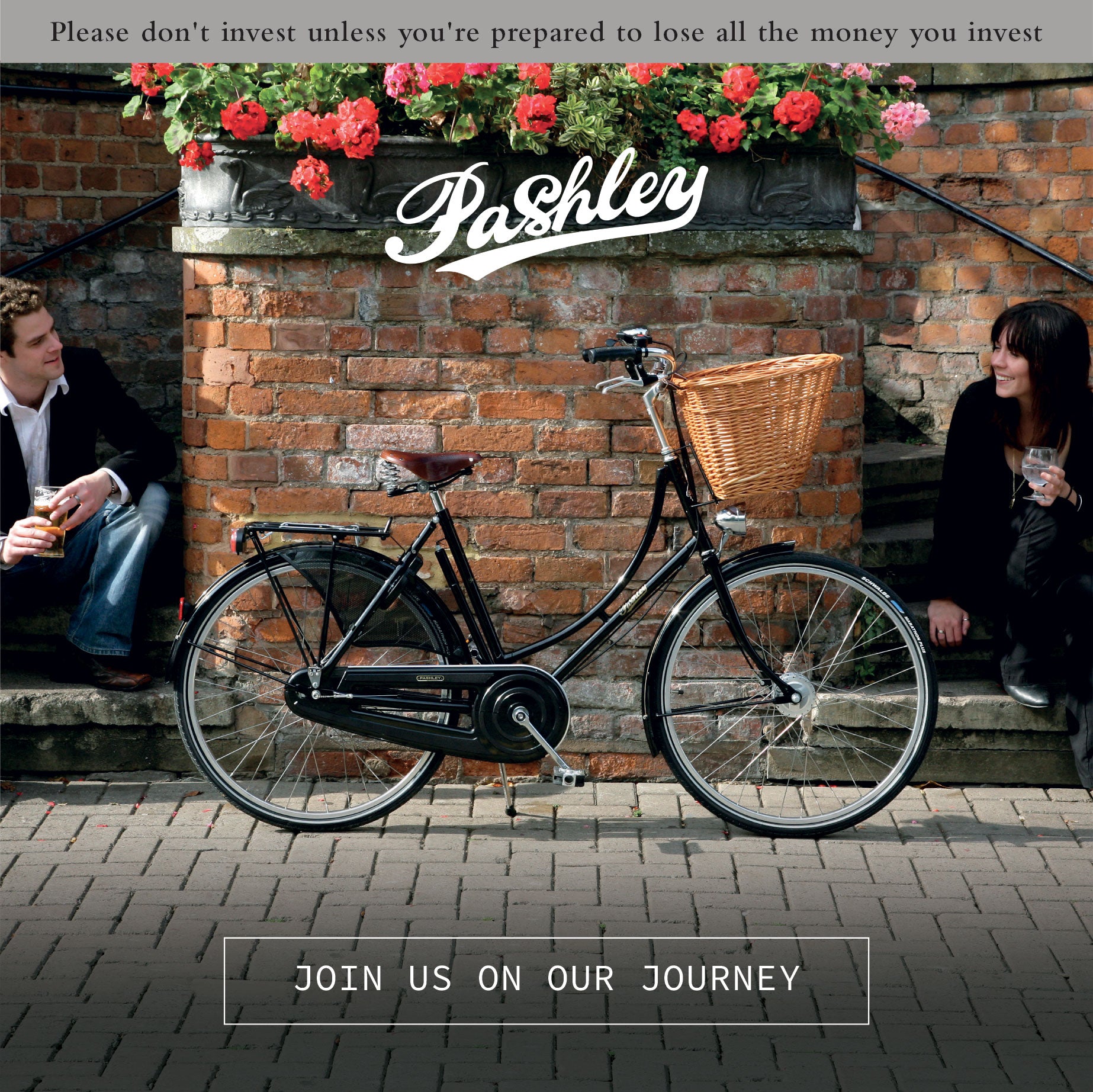 Couple holding drinks sat on steps outside a pub alongside a classic bicycle.