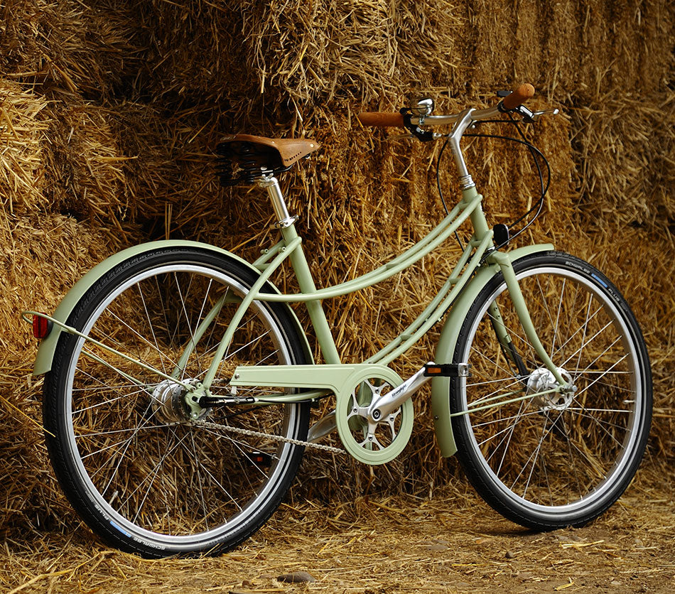 A willow green Pashley Penny bicycle next to some hay bales on a farm.