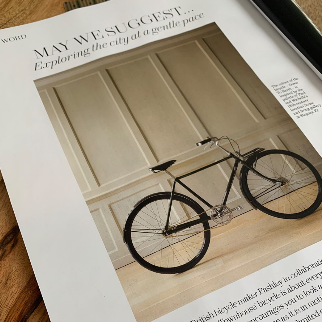 An open magazine showing The Townhouse Bicycle pictured inside a townhouse in front of cream wooden panelling