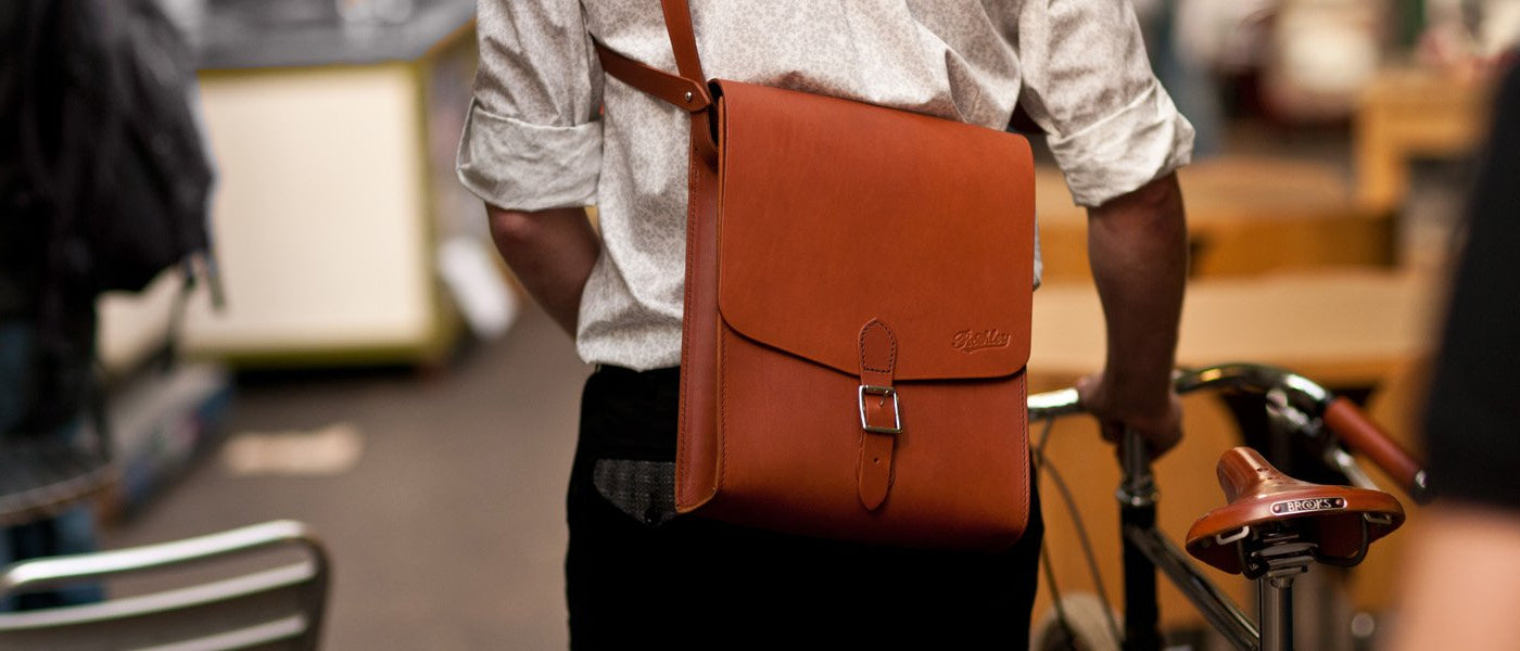 A gentleman wearing a Pashley leather despatch bag whilst pushing his Guv'nor through a food market.