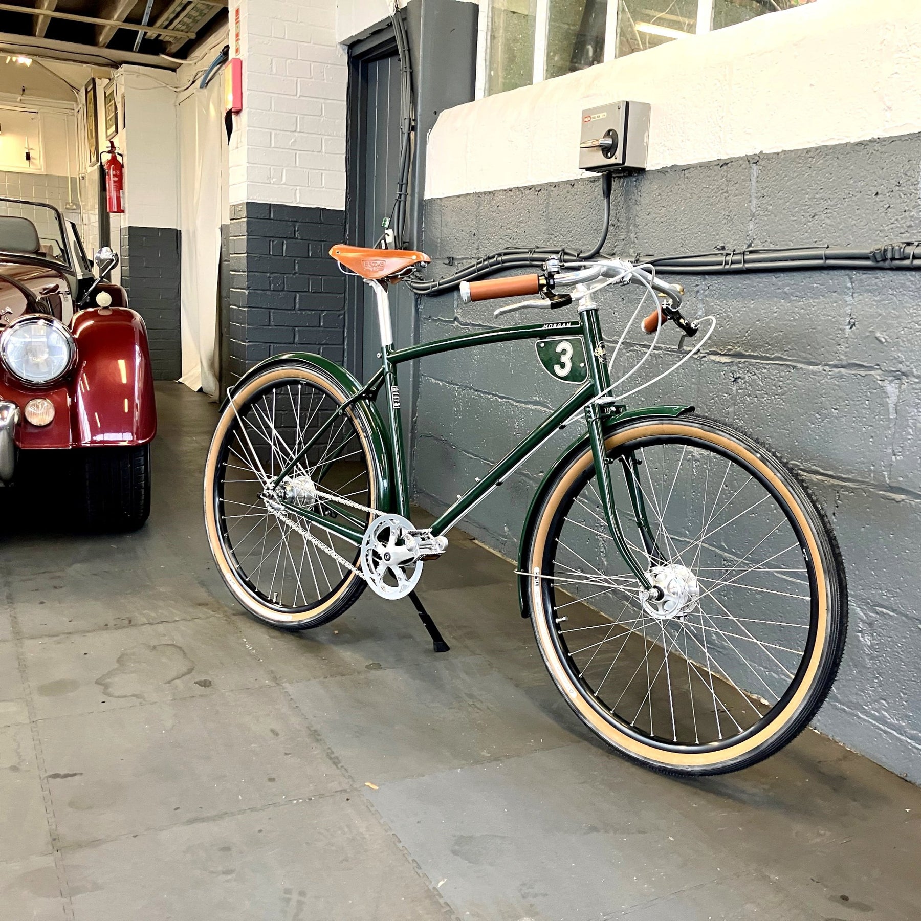 a Morgan 3 bicycle next to a morgan car