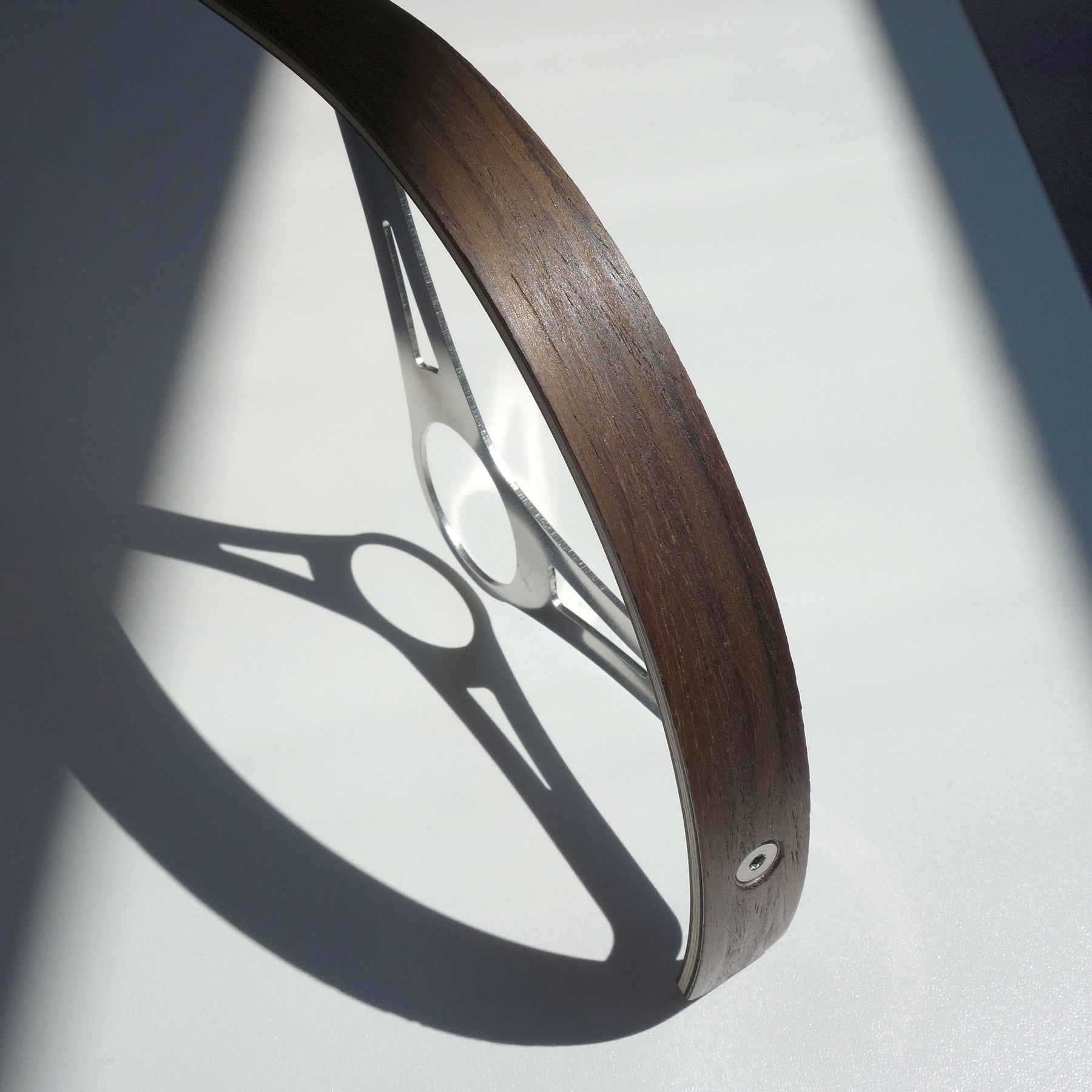 Close-up of walnut wood bicycle chainguard with stainless steel bracket.