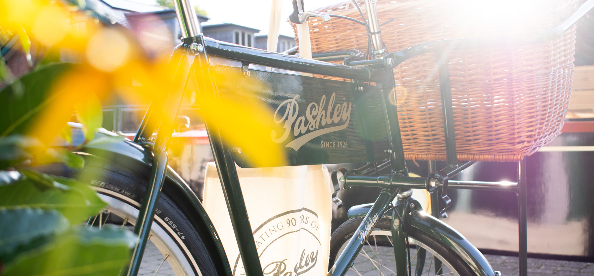A close-up of the Pashley butchers style bike, showing it's advertising nameplate attached to it's frame. It also has a large front cargo basket.