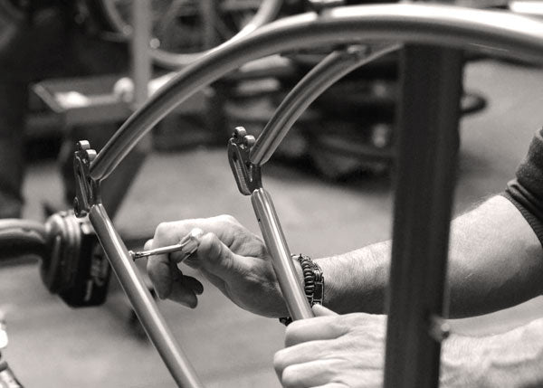 Close-up of hands assembling components to a bicycle frame inside the Pashley factory.