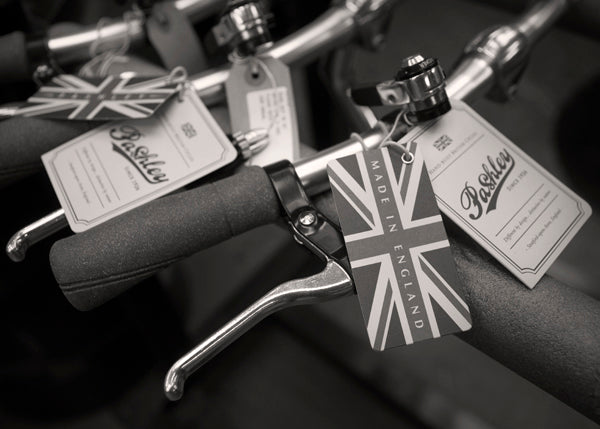 Close-up of a row of handlebars with cork grips and union jack swing tickets.