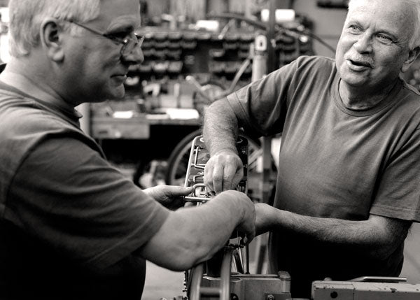 Two Pashley craftsmen working together on assembling a classic bicycle.