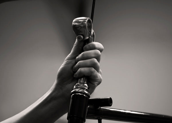 A hand pushing a handlebar stem into the headset of a bicycle frame.