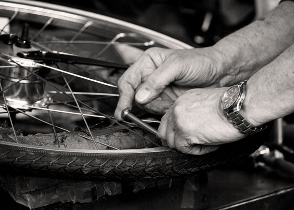 A close-up of hands fitting a tyre onto a bicycle wheel rim.