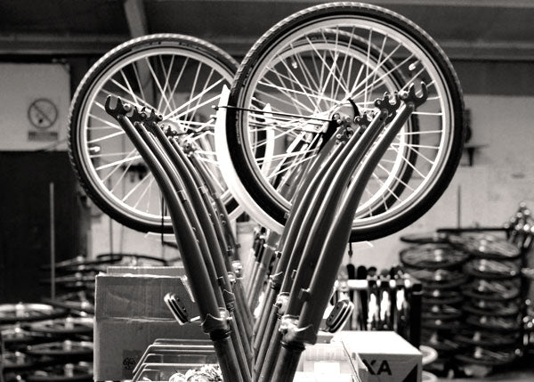 A row of bicycle forks and wheels ready to be fitted on to bikes.