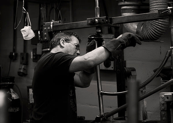 A Pashley craftsman aligning a classic bicycle frame in a jig.