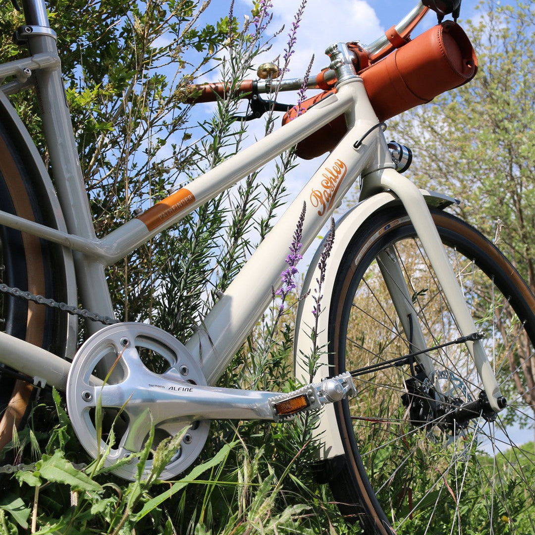 Pashley Pathfinder bicycle with a leather handlebar bag, parked amongst some flowers