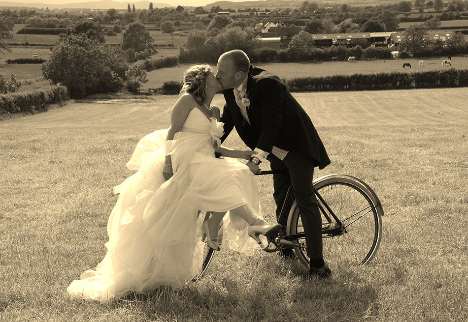 A couple sitting and kissing on a Pashley Britannia Bicycle on their wedding day.