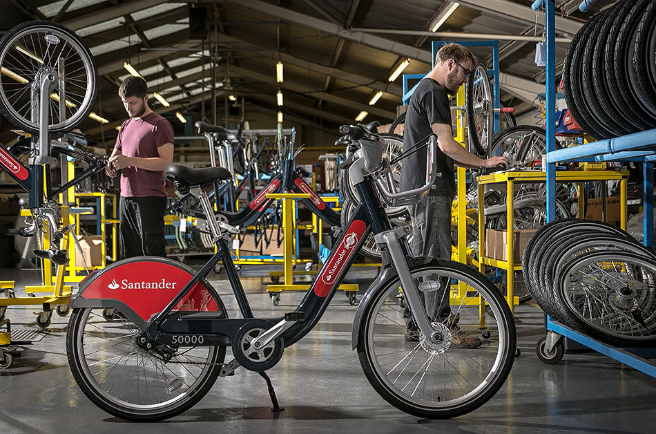 Pashley Santander London hire bike in the Pashley factory with two bike builders working behind.