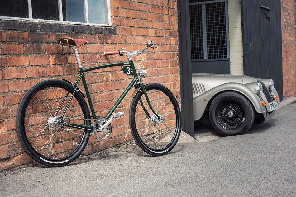 British Racing Green Pashley-Morgan classic bicycle sitting next to the bonnet of a Morgan motor car at the Morgan factory.