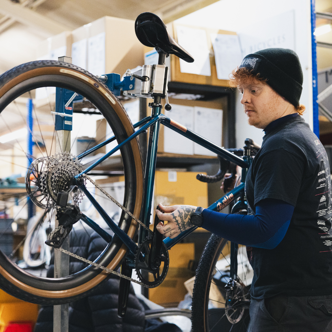 A craftsman assembling a blue Roadfinder bike inside the Pashley factory