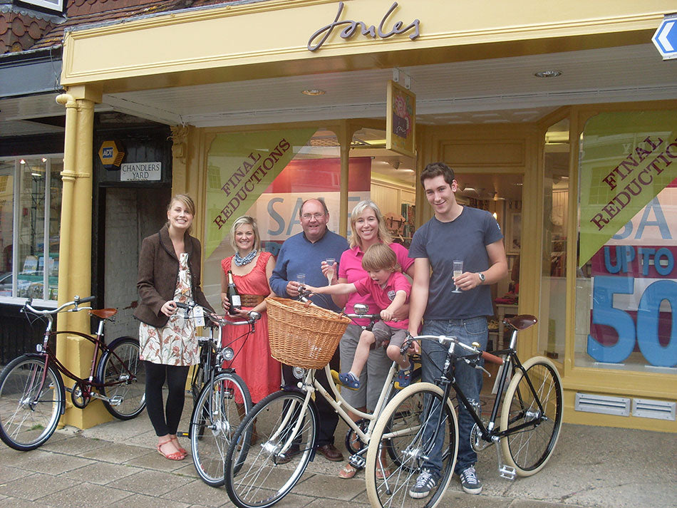 A family standing outside a yellow Joules store with the Pashley bicycles they won. 
