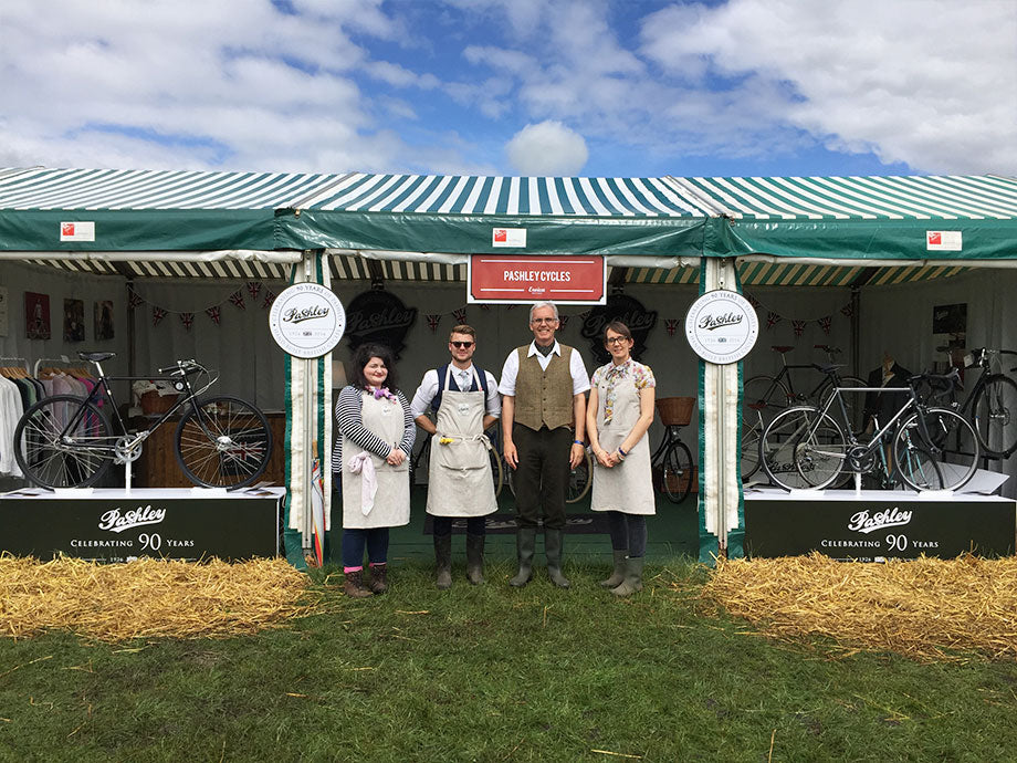 The Pashley team - Hannah, Blake, Adrian, Chloe - standing in front of the Pashley display at Eroica 2016 with blue, sunny sky behind.