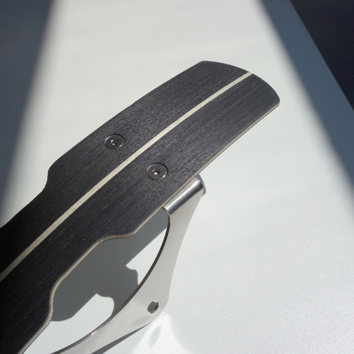 Close-up of black wooden bicycle mudguard with centre pin stripe and stainless brackets.