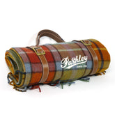Roll-up plaid blanket with leather straps and 'Pashley' branding on a white background